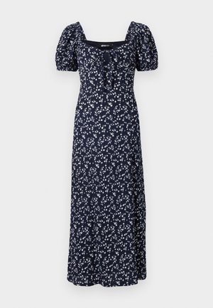 Jūras spēku ziedu maksi kleita ar puff piedurknēm, kvadrātveida dekoltē un sasienamu detaļu priekšpusē. Rotāta ar izmētātiem baltiem ziediem.