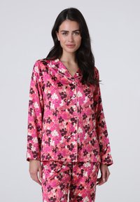 Completo pigiama floreale rosa con top con bottoni a maniche lunghe e pantaloni coordinati, realizzato in tessuto morbido con dettagli in piping bianco.