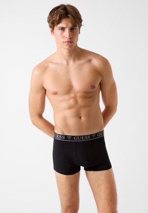 Black boxer briefs featuring a branded elastic waistband with a smooth texture and snug fit, designed for comfort and support.