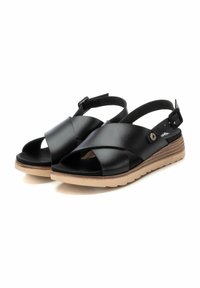 Sandali in pelle nera con design a incrocio, punta aperta, cinturino regolabile sul retro e suola in gomma naturale con finitura testurizzata.