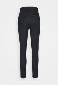 Jeans ajustados de mezclilla de lavado oscuro. De cintura alta, con dos bolsillos traseros y un corte slim hasta el tobillo. Textura suave con un detallado minimalista.