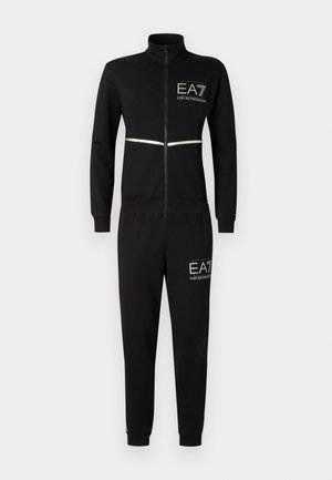 Musta sportlik ülikond pehmest kangast, kõrge kaelusega, ees luku ja helkurtriibuga. Logo on trükitud rinnale ja reiele.