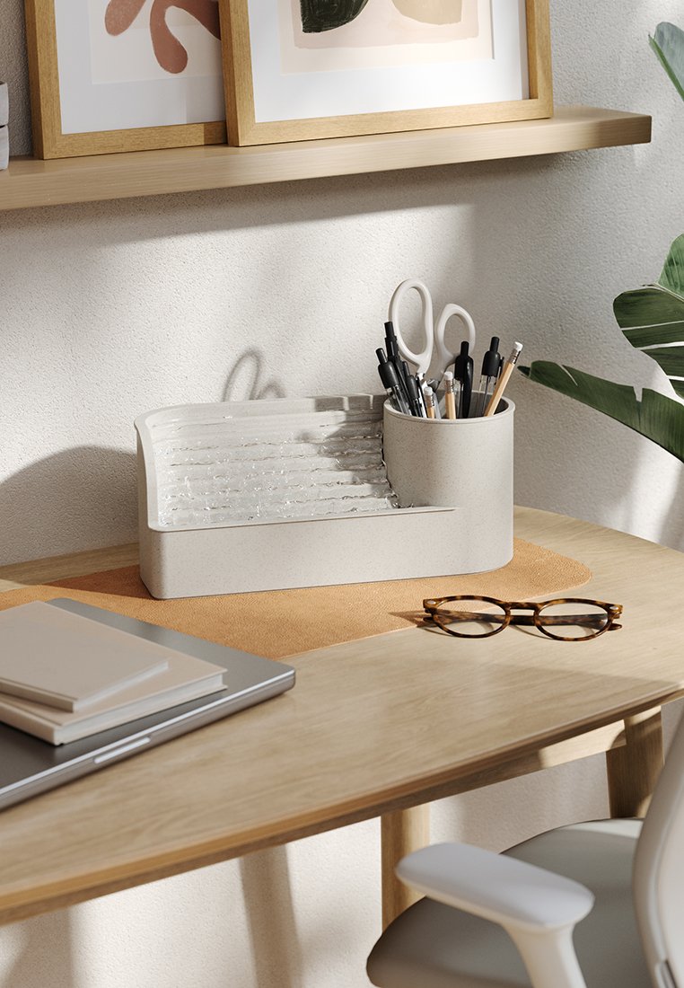 Helle graue Schreibtisch-Organizer mit einem strukturierten Trenner, der Stifte und Scheren hält. Auf einem Holztisch mit einer dekorativen Unterlage, einem Laptop und einer Brille platziert.