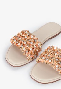 Sandali con apertura sulla punta e due cinturini embelliti. I cinturini presentano tessuto arancione, perle finte e strass trasparenti. Soletta e suola beige.