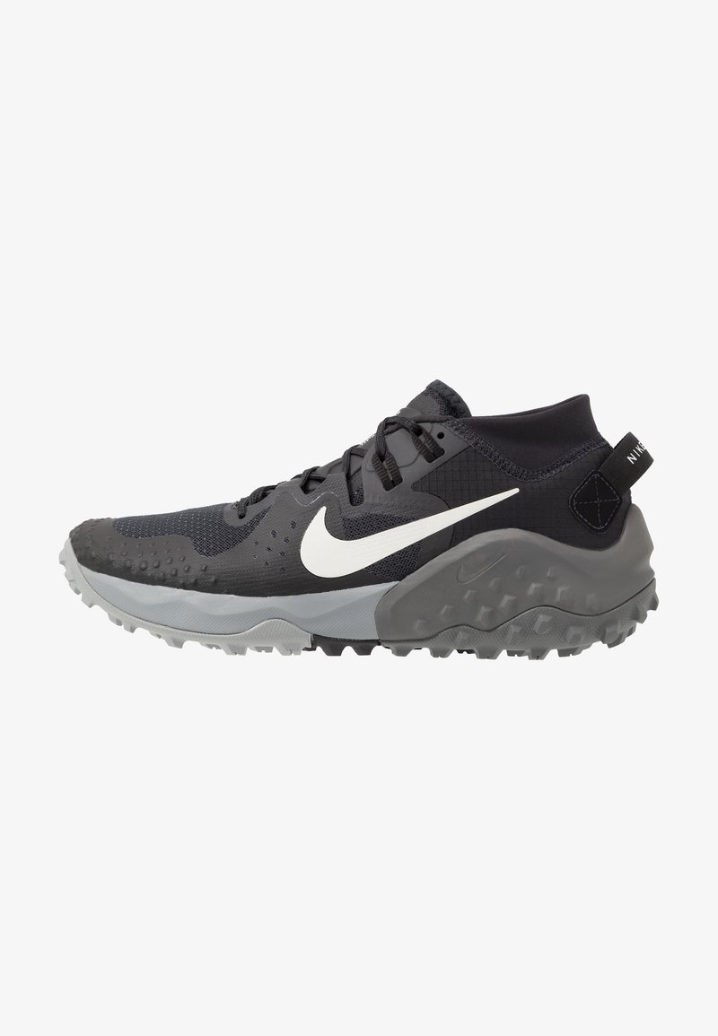 Chaussure de sport Nike noire et grise avec logo Swoosh blanc, semelle texturée et col rembourré à la cheville, conçue pour la course sur sentiers ou une utilisation en extérieur.