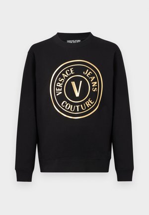 Czarna bluza z długim rękawem i okrągłym dekoltem, z złotym, okrągłym logo "Versace Jeans Couture" umieszczonym na środku przodu.