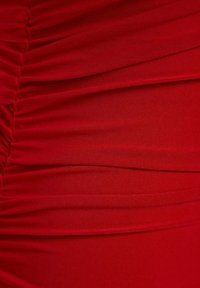 Tissu rouge vif avec fronces horizontales et diagonales créant une texture plissée et des plis.