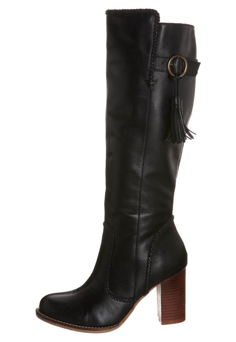 Černá kožená vysoká kozačka nad kolena s blokovým podpatkem, zdobená pletenými detaily, dekorativní třásní a kruhovým kovovým doplňkem.