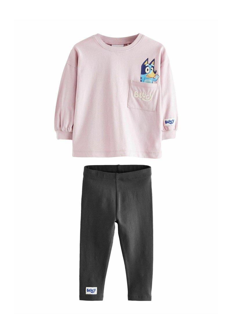 Hellblaues langärmeliges Shirt mit einem Cartoon-Hund auf der Brusttasche, kombiniert mit schwarzen Leggings; beide aus weichem, leichtem Stoff.