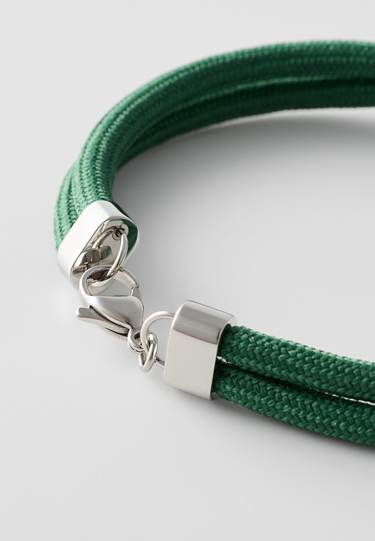 Grünes geflochtenes Seilarmband mit einem metallisch-silbernen Verschluss und Hardware. Besitzt eine glatte Textur und ein robustes Design.
