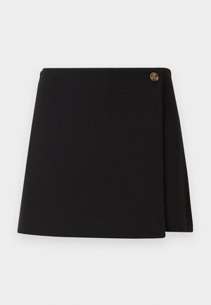 Jupe portefeuille noire avec une seule fermeture à bouton marron sur le côté supérieur droit, posée à plat sur un fond blanc.