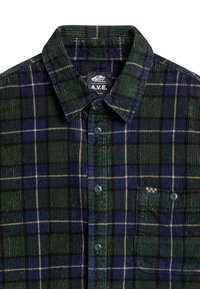 Camisa de franela de cuadros verdes y azules con diseño de botones, cuello y un bolsillo en el pecho con una pequeña etiqueta con logo. Tejido acanalado texturizado.