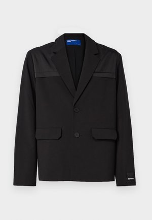 Blazer negro con un diseño estructurado, dos bolsillos delanteros, dos botones y detalles brillantes en los hombros. Fabricado con una tela suave.
