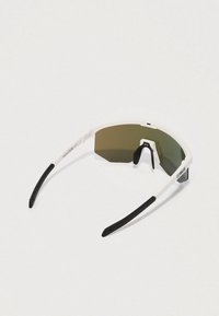 Γυαλιά ηλίου με λευκό σκελετό, μαύρα καουτσούκ στις άκρες των βραχιόνων και πράσινους φακούς με φίλτρο. Διαθέτουν ένα κομψό, γωνιώδες σχέδιο.