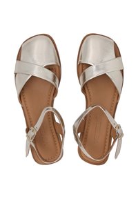 Zilveren metallic sandalen met bandjes en een vierkante neus, met kruislings in elkaar grijpen banden en een gespsluiting rond de enkel, op een lichtbruine zool.