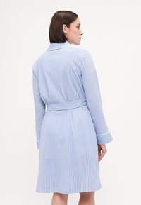 Blå och vitrandig badrock med långa ärmar, midja med bälte och sjalkrage; tillverkad av mjukt tyg med en slät textur.