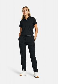 Črna polo majica s kratkimi rokavi, kombinirana s črnimi hlačami z pasom. Obleka je dopolnjena z belimi supergami, ki se osredotočajo na eleganten dizajn.