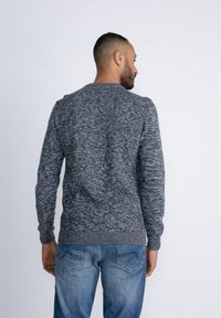 Gebreide trui in tinten van blauw en grijs, lange mouwen, ronde halslijn, geribde manchetten en zoom, gestructureerde stof, gecombineerd met lichtblauwe jeans.