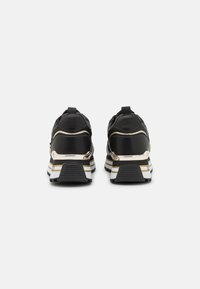 Sneaker neri con tomaia in pelle liscia, dettagli in hardware dorato e una suola spessa, a motivo bianco e nero con strisce dorate.
