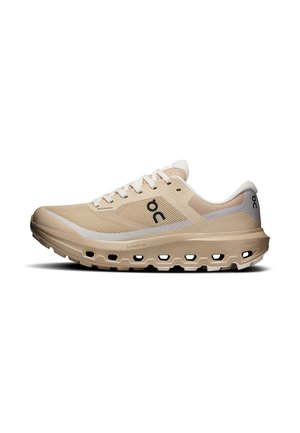 Licht beige en witte sportschoen met mesh bovenwerk, veters en dikke gevoerde zool met uitgeholde gedeelten voor demping en flexibiliteit.