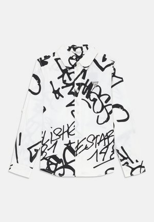 Camicia bianca a maniche lunghe con bottoni, decorata con scritte e disegni astratti in stile graffiti nero, con un piccolo logo triangolare Guess sul petto.