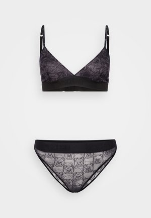 Bralet din dantelă neagră și chiloți asortați, cu un model floral și imprimeu cu urs. Bandă elastică cu logo-ul "Moschino" în negru.