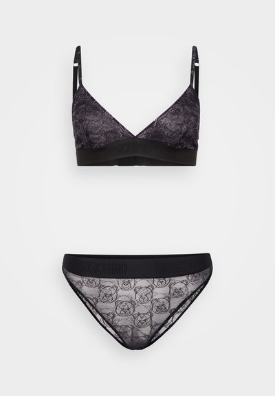 Melna mežģīņu bralette un saskaņotas biksītes, kas rotātas ar ziedu rakstu un lāču apdruku. Elastīga lente ar "Moschino" logotipu melnā krāsā.