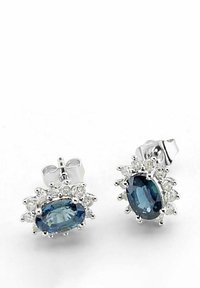 Piedras preciosas ovaladas azules rodeadas de pequeñas gemas claras en un engaste de plata, con un diseño de botón que incluye un poste y un cierre de mariposa.