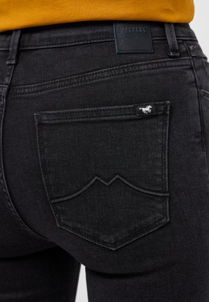 Czarne dżinsy z denimu o teksturowanym wykończeniu, zakrzywionych szwach tylnej kieszeni oraz małej białej metce z logo na prawej kieszeni.