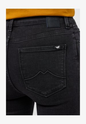 Czarne dżinsy z denimu o teksturowanym wykończeniu, zakrzywionych szwach tylnej kieszeni oraz małej białej metce z logo na prawej kieszeni.