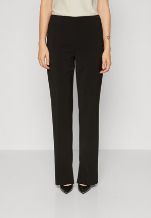 Black tailored trousers featuring a straight leg design, smooth texture, and subtle front seam detailing. Paired with pointed black heels.