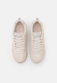 Beige suede sneakers with a textured mesh tongue, round toe, and light laces. Features a rubber outsole and branded detailing on the tongue.