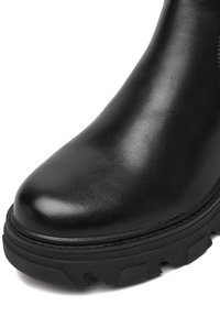 Botină din piele neagră, cu vârful rotund, parte superioară texturată și talpă neagră robustă cu crampoane pentru aderență.