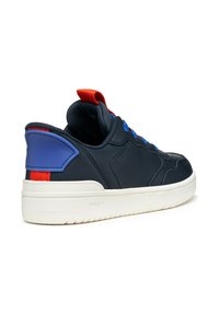 Basket en marine avec une semelle blanche, des lacets colorés en bleu et rouge, et un onglet bleu et rouge au talon. Conçue pour le confort et le style.