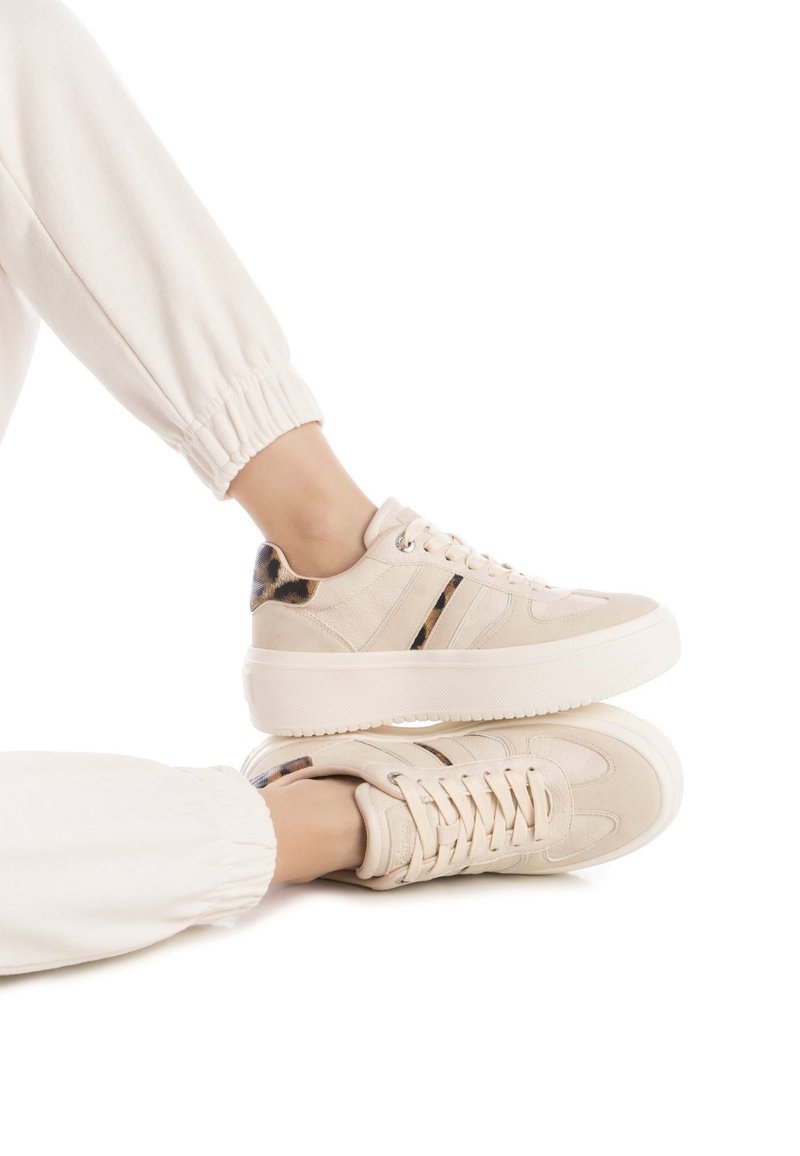 Zapatillas beige con acabado texturizado, con acentos de estampado de leopardo, suelas de goma blancas y tres franjas en contraste en el lateral.