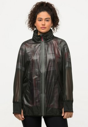 Chaqueta deportiva negra con tela de malla semitranslúcida, cuello alto, cremallera frontal, puños en color contrastante y detalles reflectantes.
