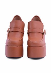 Scarpe platform in pelle marrone con punta tondeggiante, dotate di doppia cinghia con fibbia metallica e suola spessa e solida.