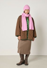 Pruun ümberõmmeldud jakk rohelise äärisega, triibuline roheline ja valge top, beež seelik, roosa põimitud sall ja sobiv müts. Pruun nahast saapad pandlaga.