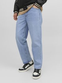 Jeans en denim bleu clair avec une coupe droite, présentant un design classique à cinq poches et portés avec des baskets noires et blanches.