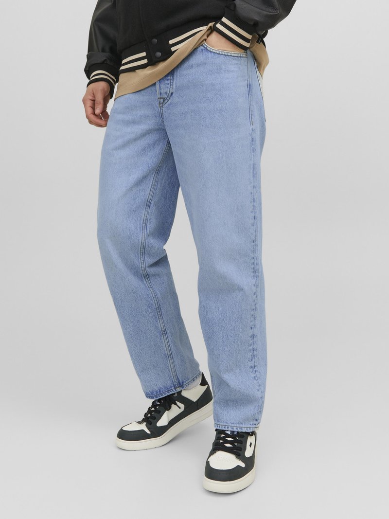 Jeans en denim bleu clair avec une coupe droite, présentant un design classique à cinq poches et portés avec des baskets noires et blanches.