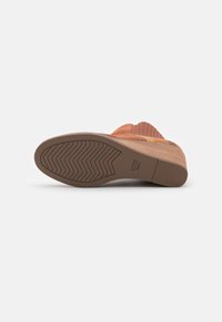 Semelle de chaussure brune avec un motif de semelle ondulé. Comprend un talon empilé en liège et un dessus en textile avec une texture nervurée et des accents de couleur.