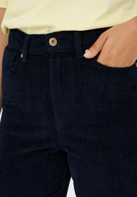 Mornarsko plavi kord pants s visokim strukom, s zatvaranjem na dugme, prednjim džepovima i teksturiranom rebrastom površinom.