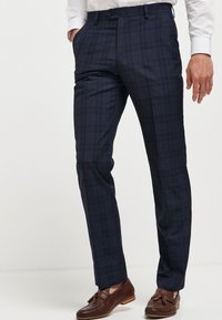 Marineblaue karierte Hose aus Stoff mit schmaler Passform, seitlichen Taschen, Gürtelschlaufen und glatter Textur.