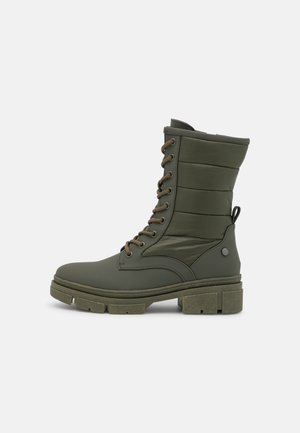 Bottes de cheville imperméables vertes avec tige rembourrée, bout rond et semelle épaisse en caoutchouc. Présentent des lacets marron et un détail de logo sur le côté.