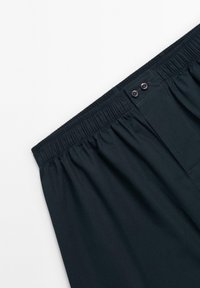 Shorts bleu marine avec ceinture élastique, dotés de deux boutons, présentant une texture lisse et un design ajusté. Aucun motif ni accent visible.