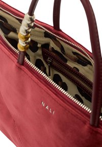 Sac à main en daim rouge avec des poignées en cuir lisse, doublé de motifs léopard, fermeture éclair en argent et un logo discret. Dispose d'une poche intérieure pour l'organisation.