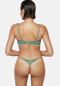 Ensemble en dentelle teal comprenant un soutien-gorge et un string avec des bretelles ajustables, un fermoir à crochets et de délicats motifs floraux sur un tissu transparent.