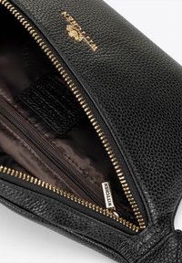 Borsa in pelle nera con hardware dorato, superficie texturizzata e chiusura con zip. L'interno presenta una foderatura scura e una tasca con zip aggiuntiva.