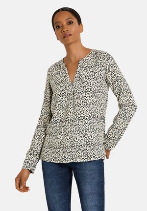 Bluse mit langen Ärmeln, die einen cremefarbenen Hintergrund und ein schwarzes Leopardenmuster hat. Sie verfügt über einen V-Ausschnitt und eine lockere Passform.