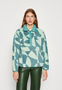 Fleece pullover in petrol en mint met geometrische patronen, voorzien van een petrolkleurige kraag, drukknoopjes en een voorkantzak. Getextureerde stof.